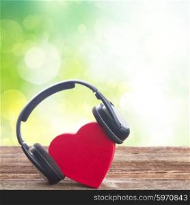 Romantic music concept - red heart with headphones with green bokeh background. Romantic music concept