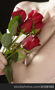 Romantic nude woman in love holding red roses in hands