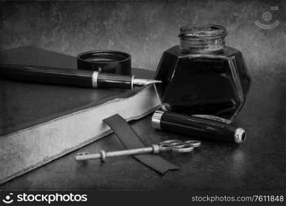 Romantic old vintage still life image of writing paraphrenalia including fountain pen ink bottle and journal book