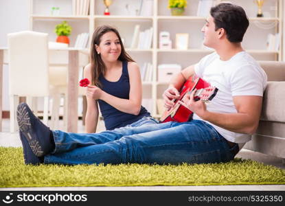 Romantic pair playing guitar on floor