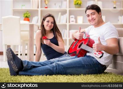 Romantic pair playing guitar on floor