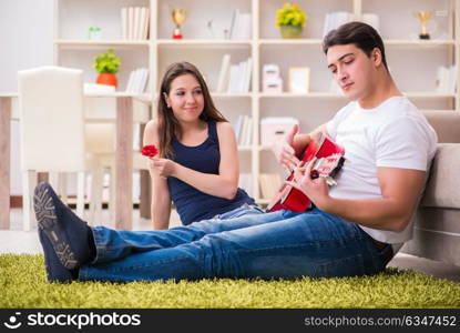 Romantic pair playing guitar on floor