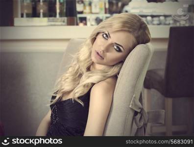 romantic portrait of blond girl sitting at restaurant . waiting somebody . she is very elegant and looking in camera