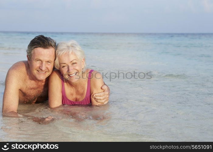 Romantic Senior Couple Lying In Sea On Beach Holiday