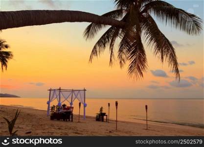 Romantic table setting on the beach at sunset