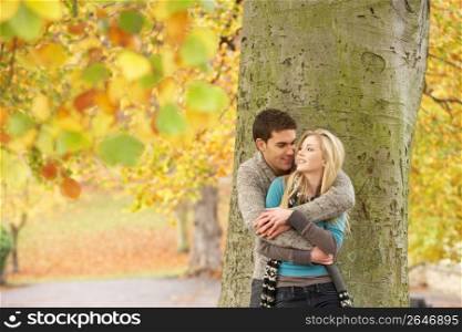 Romantic Teenage Couple By Tree In Autumn Park