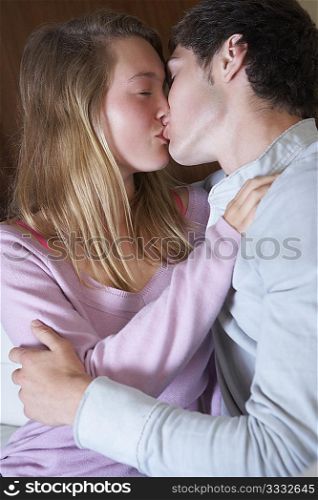 Romantic Teenage Couple Kissing On Sofa At Home Together