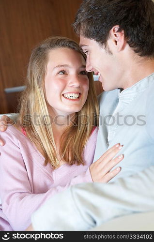 Romantic Teenage Couple Sitting On Sofa At Home Together