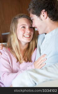 Romantic Teenage Couple Sitting On Sofa At Home Together