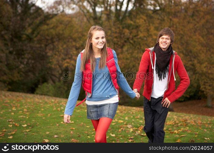 Romantic Teenage Couple Walking Through Autumn Landscape