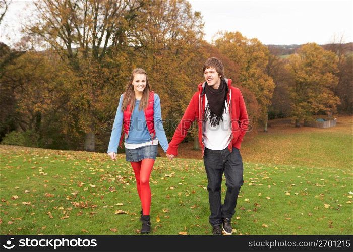 Romantic Teenage Couple Walking Through Autumn Landscape