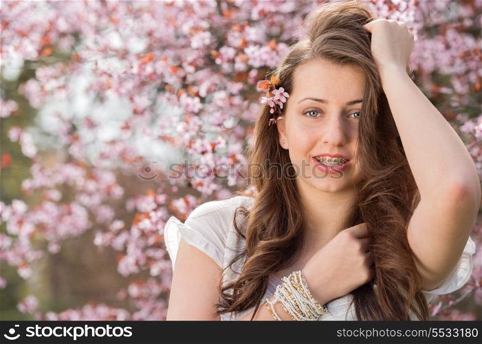 Romantic teenage girl wearing braces posing near blossoming tree spring