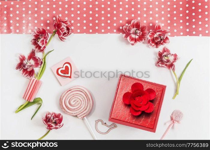 Romantic Valentines day background with hearts , red flowers, lollipop, gift box and greeting card with on white background. Top view. Frame