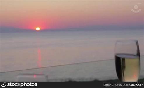 Romantic view of clinking glasses of champagne against blurred sunset sea background Piraeus, Greece