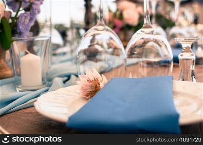 Romantic wedding or another catered event table setting, flowers, white plates, blue napkin, Easter decoration, outdoors