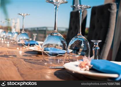 Romantic wedding or another catered event table setting, flowers, white plates, blue napkins, wine glasses, Event decoration, summer time, outdoors