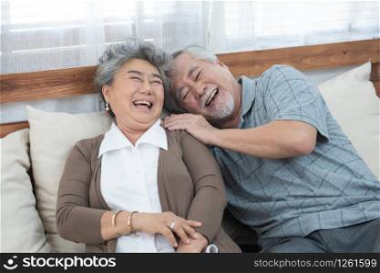 Romantic with big smile and laughing of senior elder asian grandmother and grandfather sit on couch sofa in home,retirement elder lifestyle