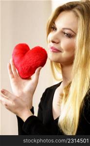 Romantic woman holding small red heart shaped fluffy pillow. Valentines day gift.. Woman holding red heart