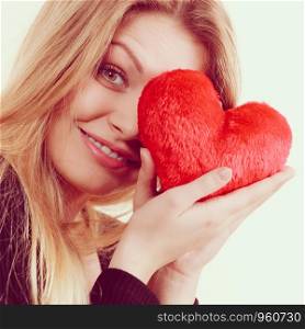 Romantic woman holding small red heart shaped fluffy pillow. Valentines day gift.. Woman holding red heart