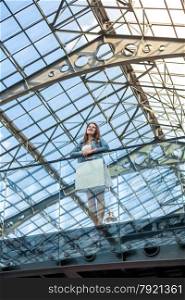 Romantic woman standing on balcony at railway station with glass ceiling