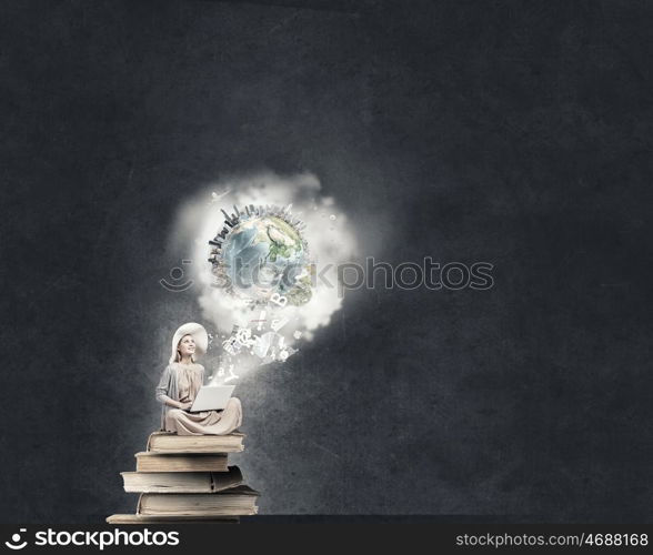 Romantic woman using laptop. Woman in dress and hat sitting on books and working on laptop. Elements of this image are furnished by NASA