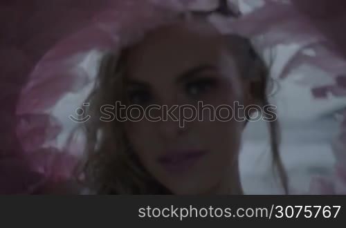 Romantic young beauty as an angel on the beach. Blonde pretty female woman wearing pink wings, feather bra and bikni bottom smiling and posing on the sandy beach over sea and sky background - video in slow motion