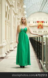 Romantic young blonde woman in green long sexy dress, indoor