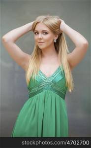 Romantic young blonde woman in green sexy dress, indoor