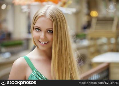 Romantic young blonde woman in green sexy dress, indoor