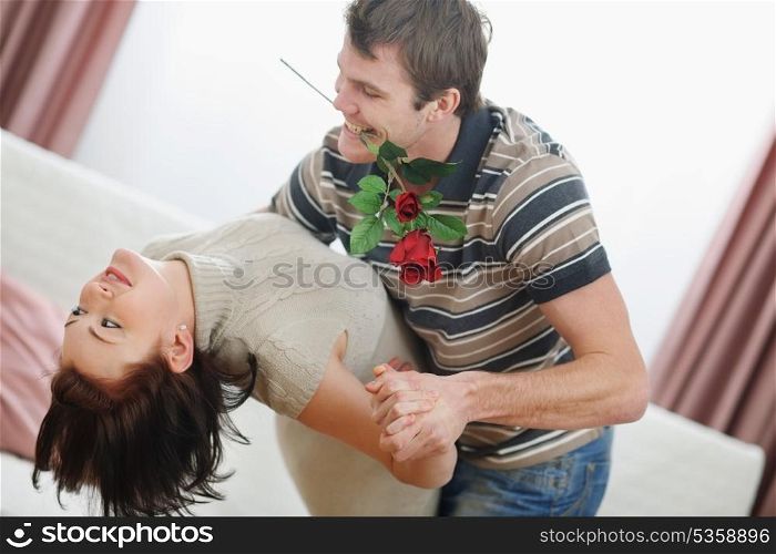 Romantic young couple dancing with red rose at home