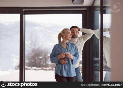 romantic young couple enjoying tea by the window on cold winter evening at home