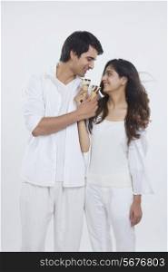 Romantic young couple feeding ice cream cones over white background
