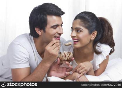 Romantic young couple having chocolate ice-cream in bed