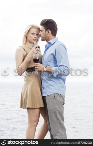 Romantic young couple having red wine against sea