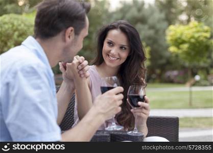 Romantic young couple having red wine in park