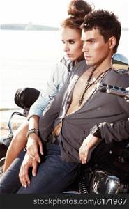 Romantic young couple in casual clothes sitting on a motorcycle.