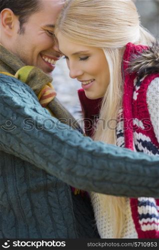 Romantic young couple in sweaters smiling at park