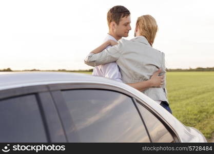 Romantic young couple leaning on car during road trip