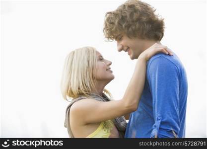 Romantic young couple looking at each other against clear sky