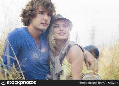Romantic young couple looking away while sitting in field