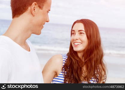 Romantic young couple on the beach. Romantic young couple standing on the beach looking at each other