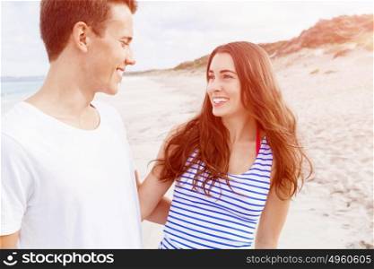 Romantic young couple on the beach. Romantic young couple standing on the beach looking at each other