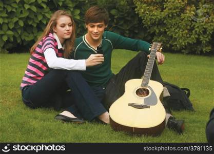 Romantic young couple relaxing outdoors in park smiling