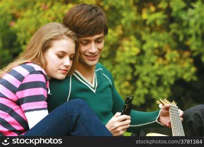 Romantic young couple relaxing outdoors in park smiling