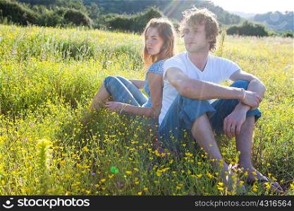 Romantic young couple sitting back to back in wildflower field, Majorca, Spain