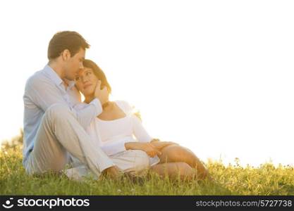 Romantic young couple sitting on grass against clear sky