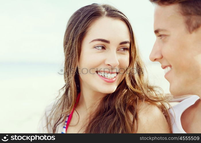 Romantic young couple sitting on the beach. Romantic young couple sitting on the beach looking at each other