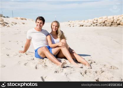 Romantic young couple sitting on the beach. Romantic young couple sitting on the beach looking at the ocean