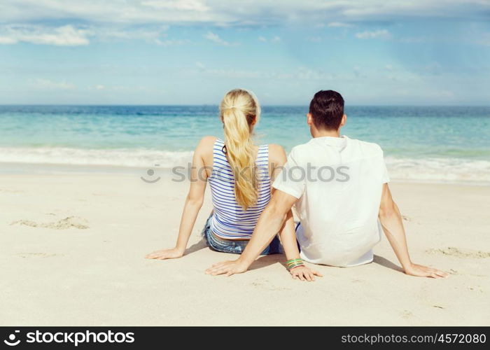 Romantic young couple sitting on the beach. Romantic young couple sitting on the beach looking at the ocean