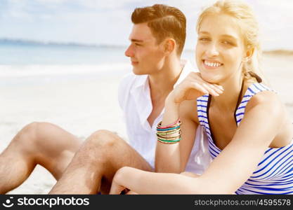 Romantic young couple sitting on the beach. Romantic young couple sitting on the beach looking at each other